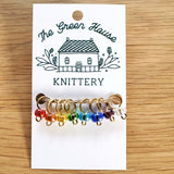 translucent red, orange, yellow, green, light blue, dark blue, purple and white glass bead ring-style stitch markers in the rainbow colourway with gold wire