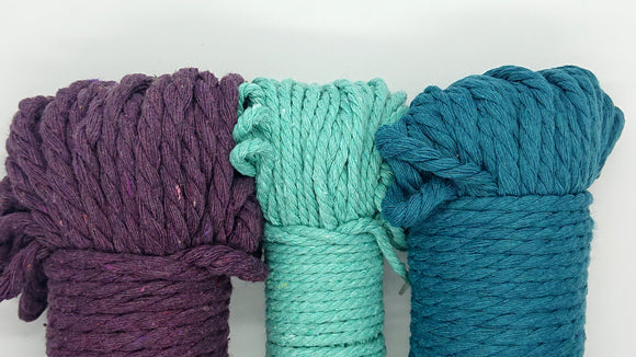 Three skeins of macramé cord, one 4 mm cord skeins between two 5 mm cord skeins.  Colours are a plum purple, light turquoise, and teal.