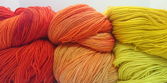 Three skeins of tonal yarns from Yukon dyer Random String Generator.  Colours are a reddish orange, light orange, and yellow.