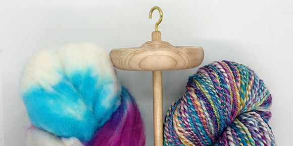 Hand-dyed merino roving, drop spindle, and hand-spun yarn.